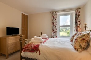 A bedroom with a bed, a wooden dresser, a television, and a window with curtains. - 2 Bed in Hawes (oc-ds052) (Hawes)