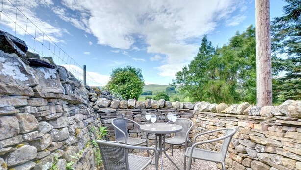A stone wall, a round table with two chairs, and a glass of white wine.