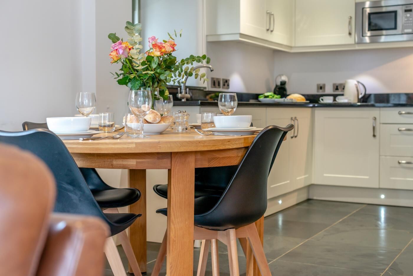 Une table à manger dressée avec de la vaisselle, des assiettes et un vase rempli de fleurs.