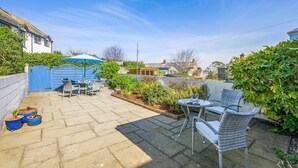 A patio with outdoor furniture, a blue gate, and a garden area. - 3 Bed in Padstow (oc-p00550) (Padstow)