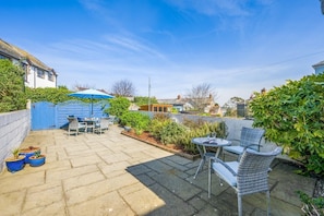 A patio with outdoor furniture, a blue gate, and a garden area. - 3 Bed in Padstow (oc-p00550) (Padstow)