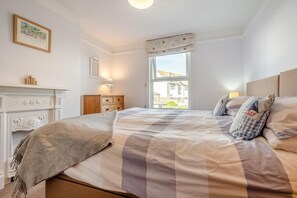 A bedroom with a bed, a dresser, a window with a view, and a fireplace. - 3 Bed in Padstow (oc-p00550) (Padstow)