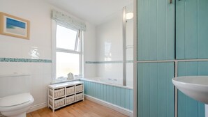 A bathroom with a toilet, a window with a view, a bathtub, and a sink. - 3 Bed in Padstow (oc-p00550) (Padstow)