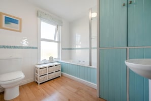 A bathroom with a toilet, a window with a view, a bathtub, and a sink. - 3 Bed in Padstow (oc-p00550) (Padstow)