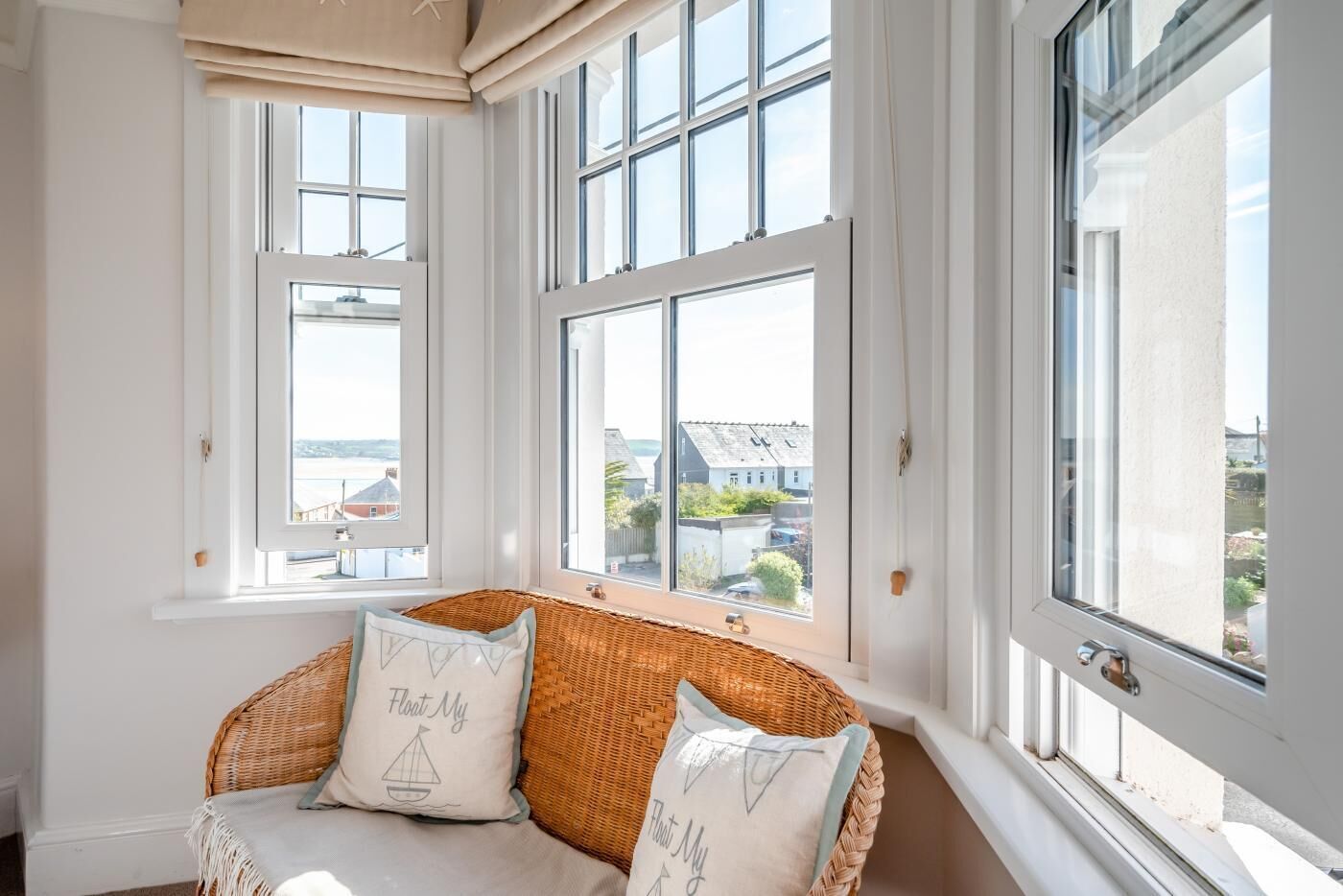 A room with large windows, a wicker sofa, and a view of the sea.
