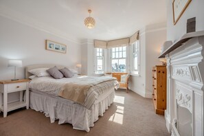 A bedroom with a large bed, bedside tables, a dresser, and a window with a view. - 3 Bed in Padstow (oc-p00550) (Padstow)