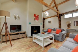 Ein Wohnzimmer mit Kamin, Fernseher und einer Couch.