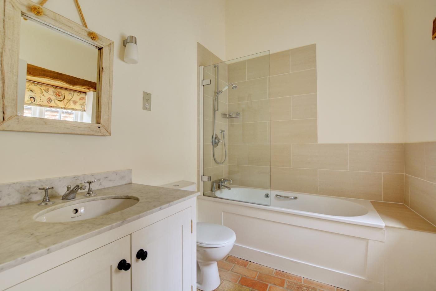 A bathroom with a marble sink, a glass-enclosed shower, and a white toilet.