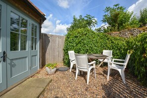Eine Terrasse im Freien mit Tisch und Stühlen, einer Tür und einer Steinmauer.