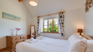 A bedroom with a large bed, wooden dresser, and a window with curtains. - 2 Bed in Roughton (oc-1734) (Roughton)