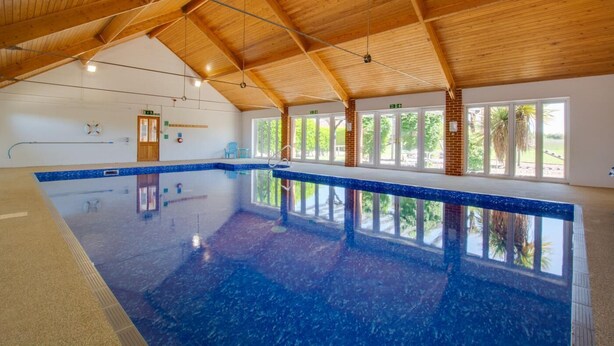 An indoor swimming pool with a wooden ceiling and large windows. - 2 Bed in Roughton (oc-1734) (Roughton)