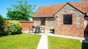 A brick house with a tiled roof, a stone wall, and a patio with a table and chairs. - 2 Bed in Roughton (oc-1734) (Roughton)
