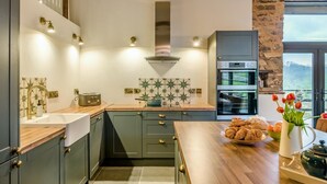 A kitchen with a wooden countertop, a built-in oven, and a view of the outdoors. - 3 Bed in Dulverton (oc-t32975) (Brushford)