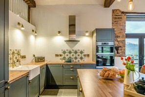 Eine Küche mit Holzarbeitsplatte, einem eingebauten Backofen und Blick ins Freie.