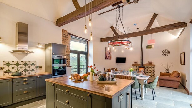 A modern kitchen with a large island, built-in appliances, and a dining area with a fireplace. - 3 Bed in Dulverton (oc-t32975) (Brushford)