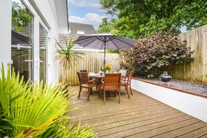 A wooden deck with a table and chairs, surrounded by a wooden fence and greenery. - 3 Bed in St. Merryn (oc-p00569) (Saint Merryn)