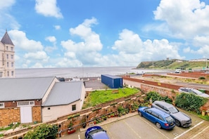 A coastal view with a building labeled 'CLIFTON,' a parking area with cars, and a body of water in the background. - 2 Bed in Scarborough (oc-s509) (Scarborough)