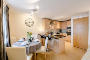 A modern kitchen with a central island, wooden cabinets, and a dining area with a round table and chairs. - 2 Bed in Scarborough (oc-s509) (Scarborough)