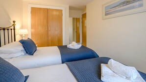 Ein Hotelzimmer mit zwei Betten, einem Holzschrank, einem gerahmten Bild an der Wand und einer Lampe auf dem Nachttisch.
