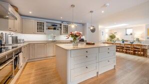 Une cuisine moderne dotée d’un îlot central, de planchers en bois et de luminaires suspendus.