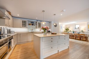 Une cuisine moderne dotée d’un îlot central, de planchers en bois et de luminaires suspendus.