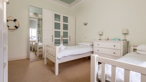 Ein Schlafzimmer mit einem weißen Bett, einem Schminktisch, einem Nachttisch und einem Spiegel.