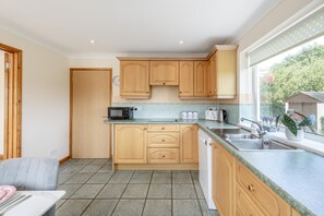 A kitchen with wooden cabinets, a microwave, a toaster, and a sink.