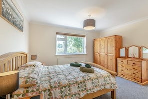A bedroom with a bed, a dresser, a window, and a painting on the wall.