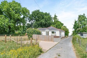 A single-story mobile home with a fenced yard, a gravel driveway, and a small garden with yellow flowers.