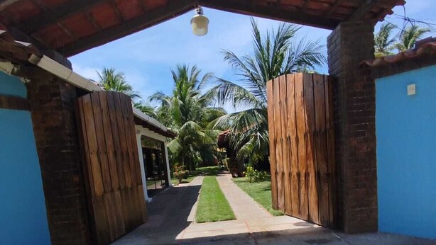 Un chemin menant à un bâtiment doté d’une porte en bois et d’un toit recouvert de tuiles.