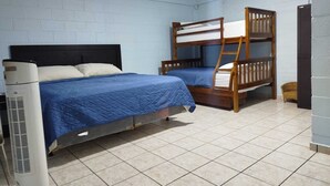 Une chambre avec un lit simple, un lit superposé et un radiateur portatif.