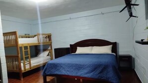 Een kamer met een enkel bed, een houten stapelbed en een klein nachtkastje.