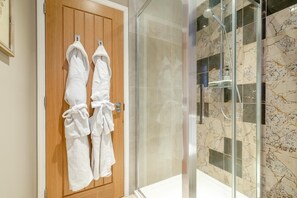 A bathroom with a wooden door, two white towels hanging on hooks, and a glass shower enclosure with marble tiles. - 1 Bed in Twyford (oc-c33411) (Twyford)