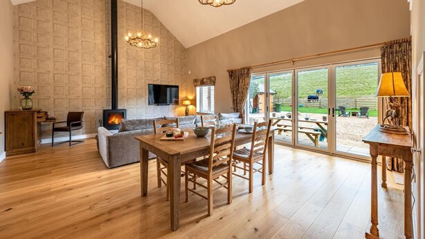 Amplia sala de estar con chimenea, comedor y grandes puertas correderas de vidrio que dan a un patio exterior.