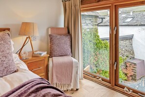 A bedroom with a large window, a bedside table with a lamp, and a view of a garden and buildings outside. - 2 Bed in Troutbeck (oc-c33392) (Troutbeck)