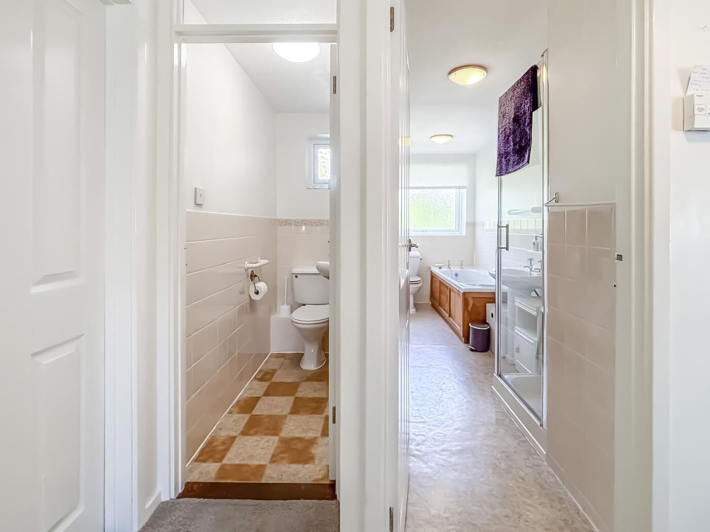 Un baño con inodoro, lavabo y bañera, suelo a cuadros y paredes blancas.