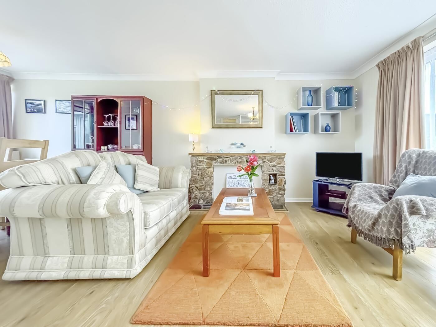 A living room with a sofa, a coffee table, a fireplace, a TV, and a bookshelf.