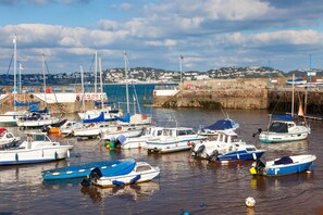 A marina with various boats docked, a stone wall, and a distant view of a town. - 3 Bed in Paignton (oc-bc1890) (Paignton)