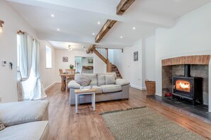 Una sala de estar acogedora con un sofá, una mesa de centro, una chimenea y una escalera que sube a un nivel superior.