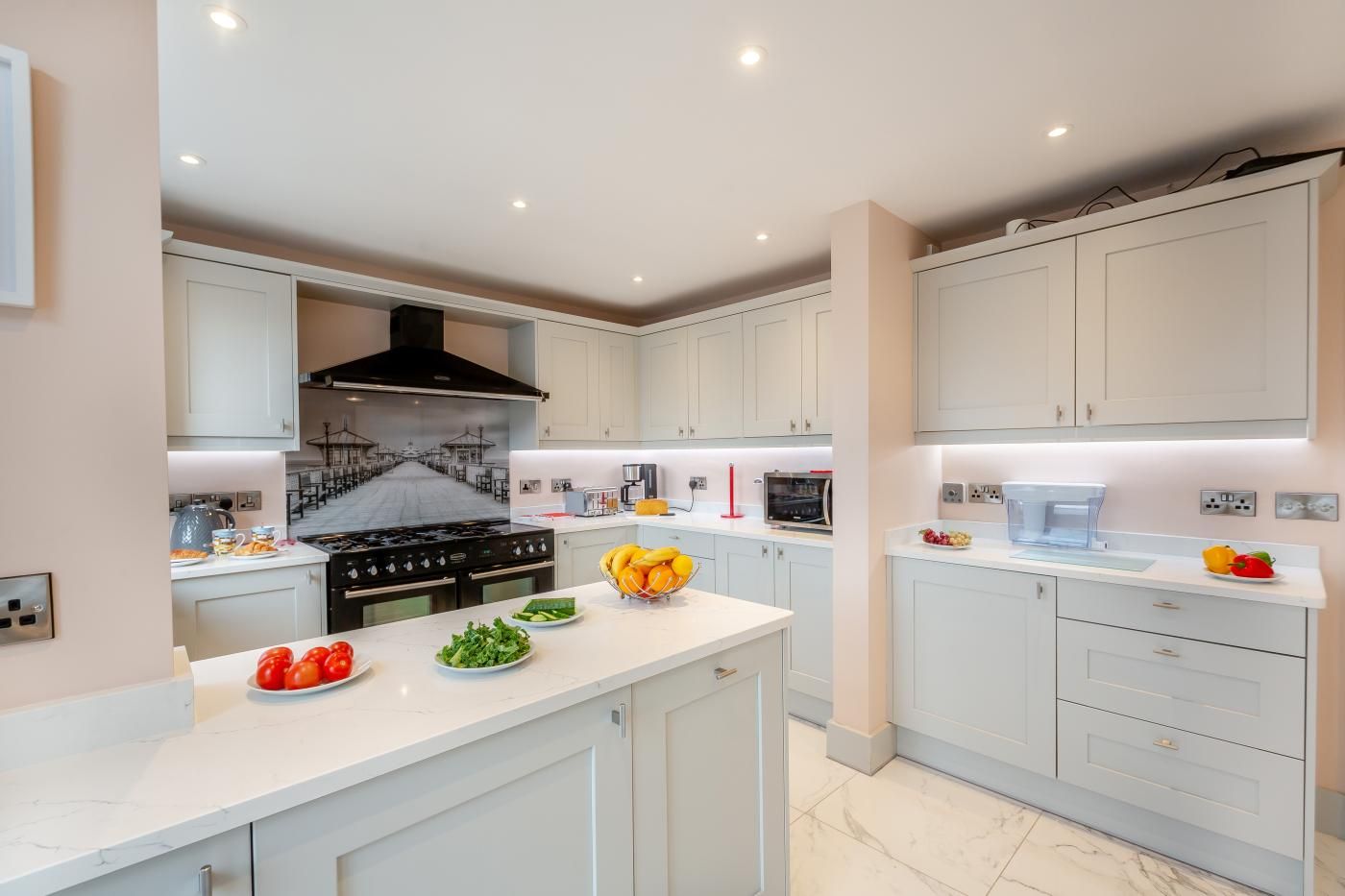 A modern kitchen with white cabinets, a central island, and a black stove.