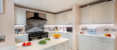 A modern kitchen with white cabinets, a central island, and a black stove.