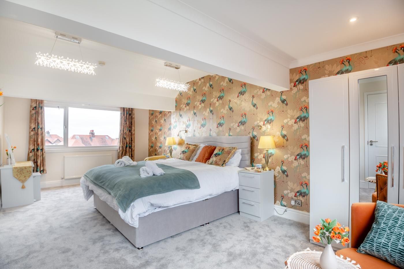 A hotel room with a bed, bedside tables, a wardrobe, and a view of the outside.