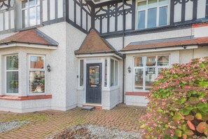 A two-story house with a bay window, a front door, and a small porch area. - 6 Bed in Llandudno (oc-s33417) (Llandudno)