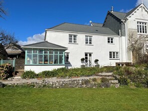 A two-story house with a conservatory, stone wall, and a well-maintained lawn. - 2 Bed in Bere Alston (oc-bctang) (Bere Alston)