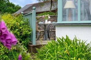 Ein Garten mit einem Tisch, Stühlen, einer Lampe und einer Steinmauer.