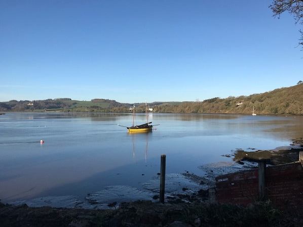 Un lac paisible, avec un petit bateau jaune amarré près du rivage, entouré de collines et d’une végétation clairsemée.