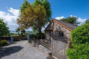 A stone building with a wooden fence, gravel driveway, and a view of the sea. - 2 Bed in Bere Alston (oc-bcdrif) (Bere Alston)