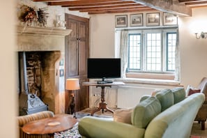 Ein gemütliches Wohnzimmer mit Kamin, Fernseher und einem Fenster mit Vorhängen.