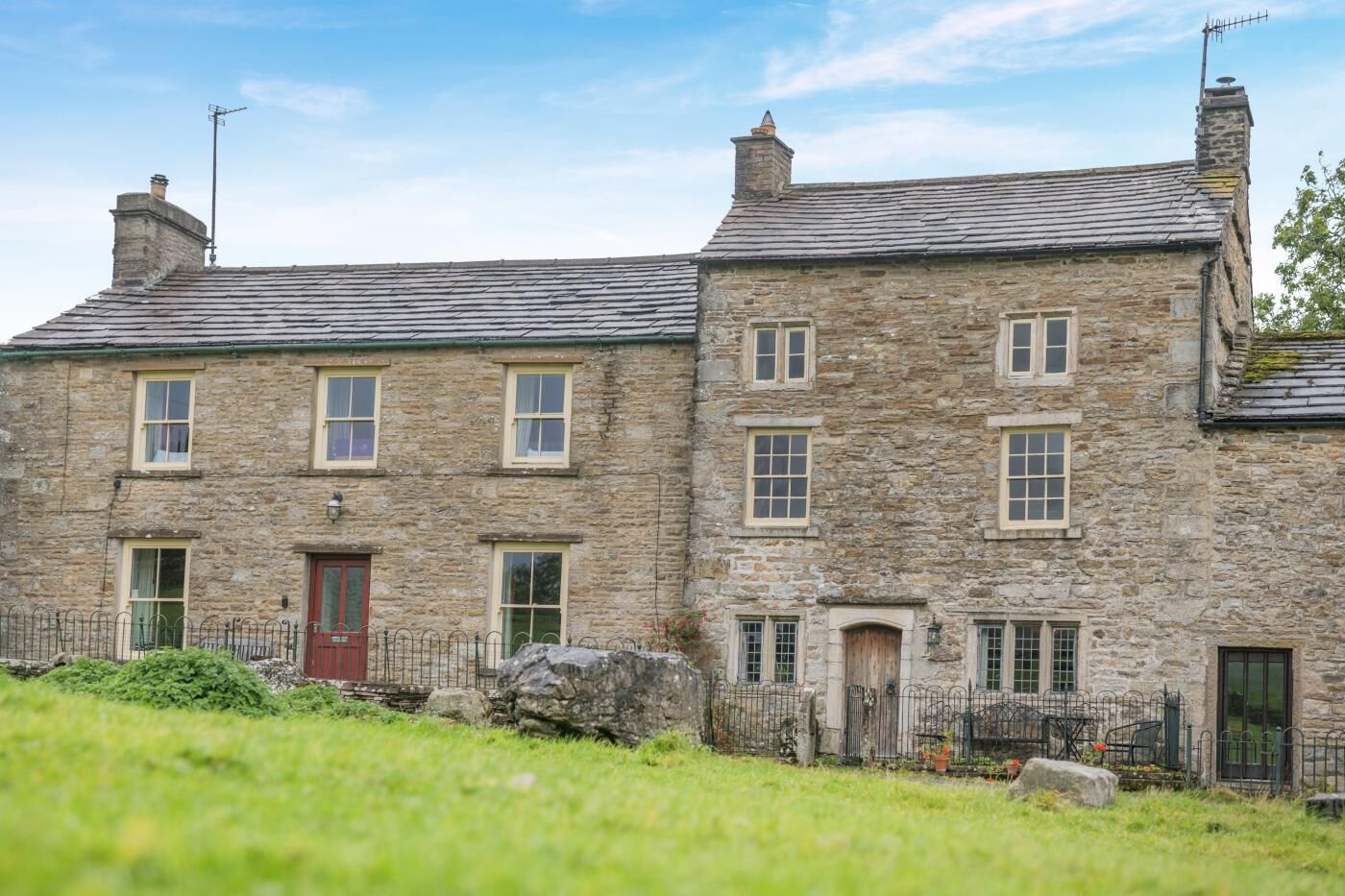 A stone building with multiple windows and a red door.