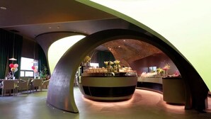 A modern interior with a central round table, curved architectural elements, and a seating area with chairs. - Beijing Bolly Wood Hotel-Guomao SKP  (Beijing)